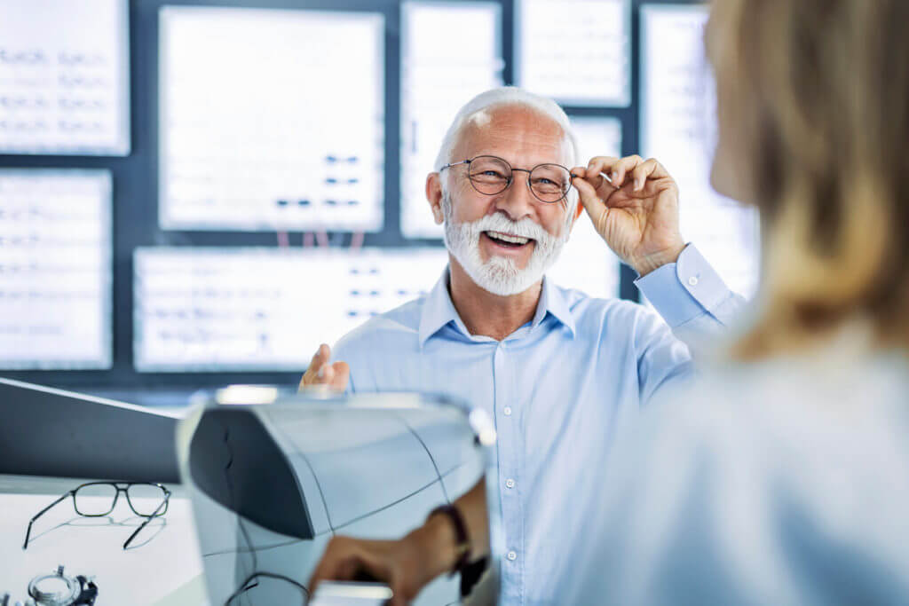 Older man happily wearing his new pair of glasses after seeing the best eye doctor in Miami.