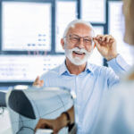 Older man happily wearing his new pair of glasses after seeing the best eye doctor in Miami.